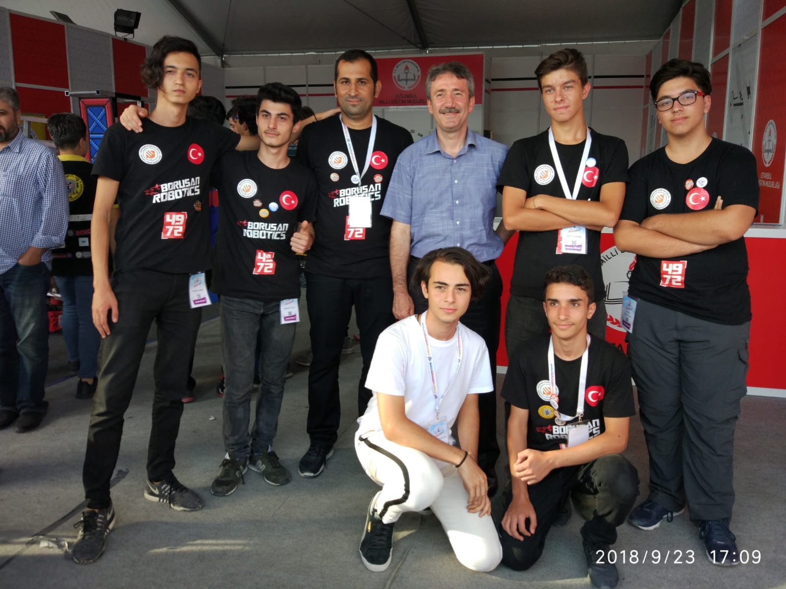 Takım üyeleri siyah takım tişörtleriyle bir etkinlik alanında